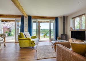 sala de estar con sofá, sillas y puertas correderas de cristal en Bewl Water View, en Ticehurst