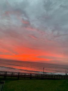 een zonsondergang boven de oceaan met een hek bij ikhay'olwandle in East London