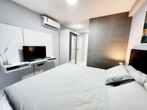 a white bedroom with a bed and a tv at Cobertura em Ondina in Salvador