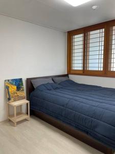 a bedroom with a blue bed and a table at Marong House in Geoje