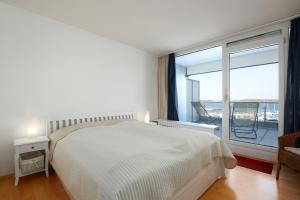 a white bedroom with a bed and a large window at BRN Bootsmann in Laboe