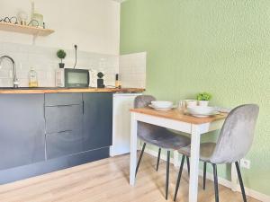 une cuisine avec une table, deux chaises et un four micro-ondes dans l'établissement Le Carnot, à 50m de la gare de Poitiers !, à Poitiers