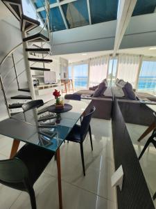 a living room with a glass table and a spiral staircase at Cobertura em Ondina in Salvador