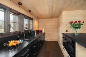 a kitchen with black cabinets and a bowl of fruit at Swiss Hotel Apartments - Gstaad in Gstaad