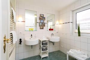 Baño de azulejos blancos con 2 lavabos y ventana en Silwai EG, en Tinnum