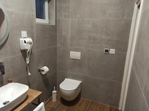 bagno con servizi igienici bianchi e lavandino di Venite Rooms a Velika