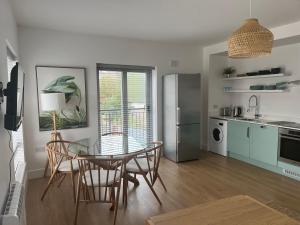 cocina y comedor con mesa de cristal y sillas en 2 Bedroom Apartment Central Town Location, en Enniscorthy