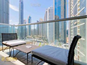 Ultima Vacation Homes loft 1 BR Apartment في دبي: شرفة مع طاولة وكراسي وإطلالة على المدينة