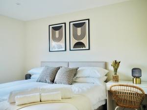 una camera con un letto bianco con due immagini sul muro di Luxurious Detached Bungalow with Private Parking a Farnborough