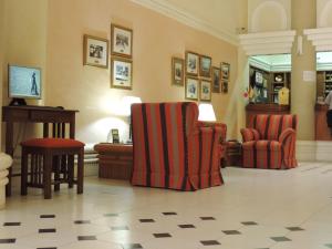 a lobby with two chairs and a desk and a piano at Hotel Galicia in Trelew