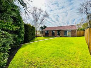 a yard with a house and a fence at Luxurious Detached Bungalow with Private Parking in Farnborough