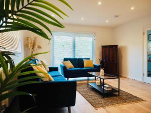 a living room with a blue couch and a table at Luxurious Detached Bungalow with Private Parking in Farnborough