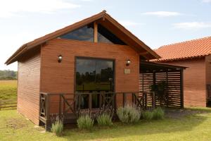 a wooden cabin with a large window in a field at Pousada Querência Tarumã in São Joaquim