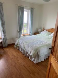 a bedroom with a large bed and a window at The Cliffs of Moher House, Doolin in Droíchead an Chláir
