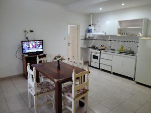 a kitchen with a wooden table with chairs and a television at "La Irma" - Complejo de Departamentos in Lincoln