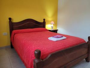 1 dormitorio con cama roja y manta roja en "La Irma" - Complejo de Departamentos en Lincoln