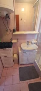 een badkamer met een wastafel, een toilet en een spiegel bij Apartment Bougainvillea in Trogir