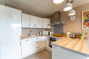 a kitchen with white cabinets and a wooden counter top at Le Mesnil - 200m des plages in Arcachon +5 photos