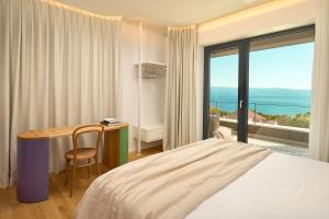 a bedroom with a bed and a desk and a window at Seaview Villa Flora - Heated pool and Spa in Omiš