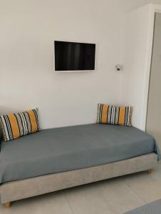 1 cama con 2 almohadas y TV en la pared en Allegro suite en Tinos Town