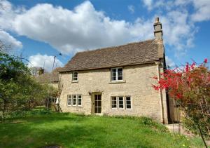 an old stone house on a grassy hill at Carters Cottage in Slaughterford