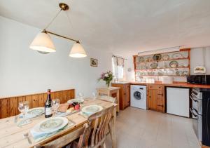 a kitchen with a wooden table with chairs and a sink at Carters Cottage in Slaughterford