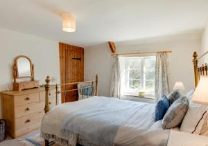 a bedroom with a bed and a dresser and a window at Carters Cottage in Slaughterford