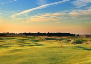 a green golf course with a red flag in the middle at Chapel House in Sandwich