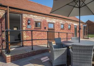 a patio with a table and chairs and an umbrella at Brighton Hopper Hut in Goudhurst