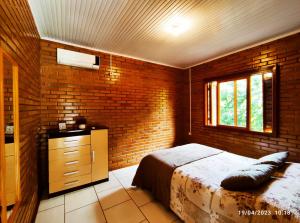 a bedroom with a bed and a brick wall at Casa de campo com acesso ao Rio in Encantado
