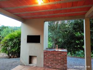 a tv on the side of a house with a brick fireplace at Casa de campo com acesso ao Rio in Encantado