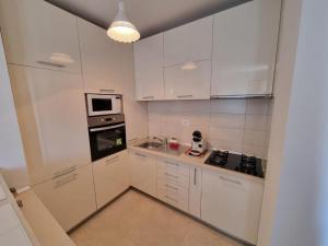 - une cuisine blanche avec des placards blancs et une cuisinière dans l'établissement Sahara Sands LOFT Private Parking, à Timişoara