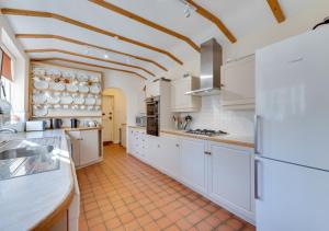a kitchen with white cabinets and a tile floor at Church Cottage in Barham