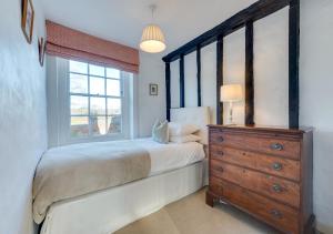 sypialnia z łóżkiem, komodą i oknem w obiekcie Church Cottage w mieście Barham
