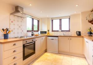 a large kitchen with white cabinets and windows at Dairy Cottage in Wadhurst