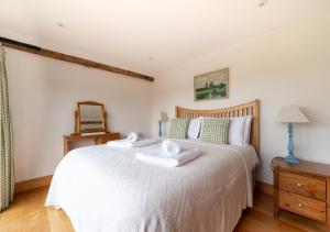 a bedroom with a white bed with towels on it at Dairy Cottage in Wadhurst