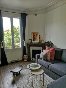 uma sala de estar com um sofá e uma mesa em Happy Place - 15 min Paris & 30 min DisneyLand - Subways - Facilities - Free parking - Secured em Maisons-Alfort