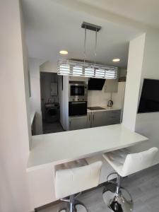 una cucina con bancone bianco e sedie bianche di Apartamento Costa de Poniente a Benidorm