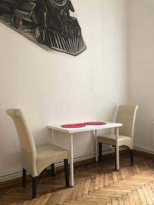 uma mesa branca com duas cadeiras e um quadro na parede em Wawel em Cracóvia