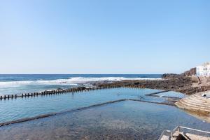 a swimming pool on the beach next to the ocean at Chalet Vacacional El Agujero in Gáldar