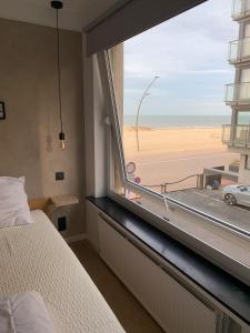 Les pieds dans le sable في دي بان: غرفة نوم مع نافذة كبيرة مطلة على الشاطئ
