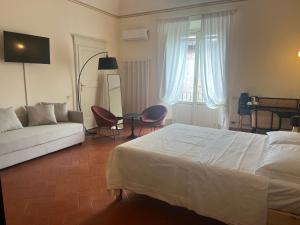 - une chambre avec un lit blanc et un canapé dans l'établissement Palazzo Rosselmini, à Pise