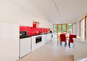 a kitchen with white cabinets and red tiles at Hazel Barn in Lyminge