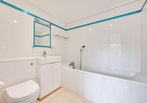 Lyminge的住宿－Hazel Barn，白色的浴室设有浴缸、卫生间和水槽。