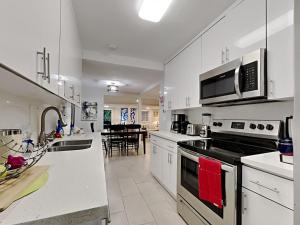 uma cozinha com armários brancos e um forno com placa de fogão em Miami Townhouse with Patio, Gazebo, Free Parking, centrally located em Miami