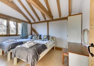 two beds in a room with wooden ceilings and windows at Glebe Cottage in Stone