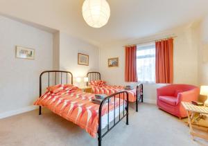 a bedroom with two beds and a red chair at Goodwin Cottage in Broadstairs