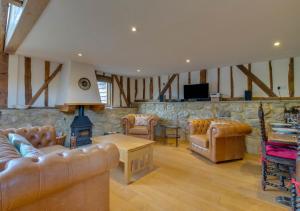 a living room with leather furniture and a stone wall at Hartley Dyke Barn in Cranbrook