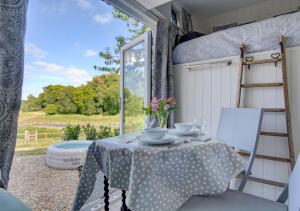 einen Tisch und Stühle in einem Zimmer mit Fenster in der Unterkunft Hattie the Horse Box in Hawkhurst