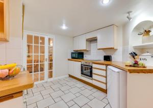 uma cozinha com armários brancos e uma bancada em Garden Flat em Sandwich